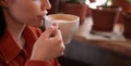 Charming young brunette woman enjoying aroma coffee in cafe holding cup with latte near her lips Royalty Free Stock Photo