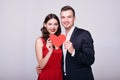 A couple of lovers sit on a gray background with a red heart in their hands