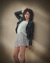 Charming young curly brunette woman in lace short skirt and black leather jacket leaning against a wall. gorgeous young woman Royalty Free Stock Photo