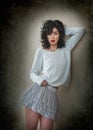 Charming young curly brunette woman in lace short skirt and white blouse leaning against wall. gorgeous young woman Royalty Free Stock Photo