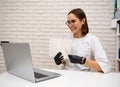 Beautiful young female doctor, general practitioner consults online while sitting at the table in hospital and showing a notebook