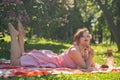 A charming young girl enjoys a rest and a picnic on the green summer grass alone. pretty woman have a holiday