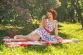 A charming young girl enjoys a rest and a picnic on the green summer grass alone. pretty woman have a holiday