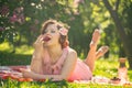 A charming young girl enjoys a rest and a picnic on the green summer grass alone. pretty woman have a holiday Royalty Free Stock Photo