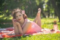 A charming young girl enjoys a rest and a picnic on the green summer grass alone. pretty woman have a holiday