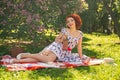 A charming young girl enjoys a rest and a picnic on the green summer grass alone. pretty woman have a holiday