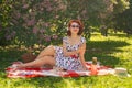 A charming young girl enjoys a rest and a picnic on the green summer grass alone. pretty woman have a holiday Royalty Free Stock Photo