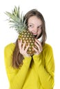 Charming young girl gnaws a large pineapple. Royalty Free Stock Photo