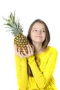 Charming young girl holds a large ripe pineapple in her hands an Royalty Free Stock Photo
