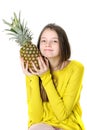 Charming young girl holds a large ripe pineapple in her hands. Royalty Free Stock Photo