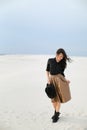 Charming young girl standing on snow and wearing brown skirt, black blouse and keeping hat in white background. Royalty Free Stock Photo