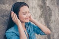 Charming young girl with toothy smile is so dreamy and happy, listening to her favourite song, holding the earphones, with closed