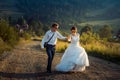 Charming young happy newlywed couple is laughing and holding hands during their walk along the countryside during teh Royalty Free Stock Photo