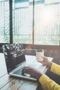 Charming young hipster girl hands working on her laptop sitting at wooden table in a coffee shop. Royalty Free Stock Photo