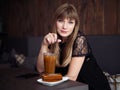 Charming young woman with beautiful smile enjoying orange juice frappe in cozy coffee shop relaxing during free time Royalty Free Stock Photo
