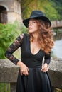Charming young light brown hair brunette woman with big black hat and blouse with lace sleeves. gorgeous young woman with cur