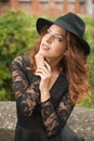 Charming young light brown hair brunette woman with big black hat and blouse with lace sleeves. gorgeous young woman with cur