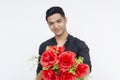 A charming young man smiling as he offers a vibrant bouquet of red roses, conveying romance and affection