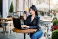 Charming young mixed raced Asian business lady with dark ponytail hair style, sitting outdoors at city cafe and reading Royalty Free Stock Photo