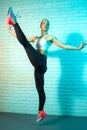 Charming young slim gymnast woman stretching on brick wall in neon lights. Flexible gymnastic exercise. Royalty Free Stock Photo