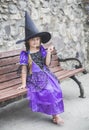 Charming young sorceress sitting with a magic wand on a bench Royalty Free Stock Photo