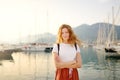 Charming young tourist woman travel by Mediterranean coast. Attractive red-haired girl on the background of sea and yachts. Yacht Royalty Free Stock Photo