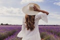 Charming Young woman with a hat and white dress in a purple lavender field at sunset. LIfestyle outdoors. Back view Royalty Free Stock Photo