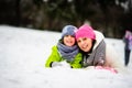 Charming young woman and her son cheerfully spend time in the winter park.