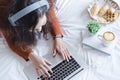 Charming young woman lying on bed and watching tv or movies streaming on laptop.