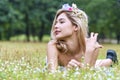 Charming woman lying relaxed on the meadow green grass with wild flowers while looking at something at outdoor. Enjoy cute Royalty Free Stock Photo