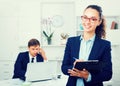 Charming young woman manager holding cardboard in office