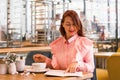 Charming young woman in pink shirt enjoying eating breakfast at cafe Royalty Free Stock Photo