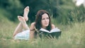 Charming young woman reading a book lying on the lawn Royalty Free Stock Photo