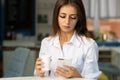 Charming young woman reading good news on mobile phone while relaxing in cafe, happy girl looking at photos on cell Royalty Free Stock Photo