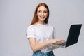 Charming young woman student holding laptop computer and looking away on isolated gray background Royalty Free Stock Photo