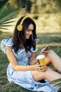 Charming young woman in summer dress listening to music with headphones while holding smartphone outdoor. Royalty Free Stock Photo