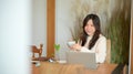 Charming young woman working on her laptop computer while sipping warm coffee Royalty Free Stock Photo