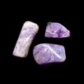 Three tumbling charoite stones on black background