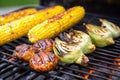 charred corn on the cob next to bbq burgers on a grill