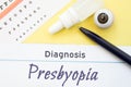 Chart for testing visual acuity, eye drops and eye anatomical model lies next to inscription Diagnosis Presbyopia. Concept for dia