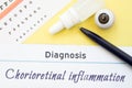 Chart for testing visual acuity, eye drops and eye anatomical model lies next to inscription Diagnosis Chorioretinal inflammation.