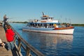 A charter fishing boat passes a young child fishing from a pier Royalty Free Stock Photo