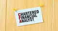 CHARTERED FINANCIAL ANALYST sign written on sticky note pinned on wooden wall