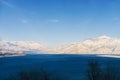 Charvak reservoir with blue water on a clear winter day in Uzbekistan, surrounded by snow-capped mountain peaks of Tien Shan Royalty Free Stock Photo