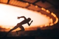 Chasing Glory: Silhouette of an Athlete, Primed for Speed, Standing Tall Amidst the Luminous Dusk at a Modern Sports Stadium. Warm