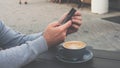 Chat with friends online on a smartphone with a cup of coffee,a man holds a phone in his hand and drinks a cappuccino. Royalty Free Stock Photo