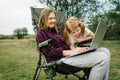 Chat online with family on laptop on picnic in nature. Homeschooling, freelance job. Mom and child. Mother work on Internet with