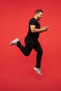 Full length portrait of young successfull high jumping man gesturing isolated on red studio background Royalty Free Stock Photo