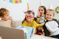 Chatting on video call little kids in party hats gathered around a laptop