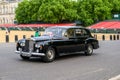Chauffeur driven Classic Rolls Royce with English flag passes Horse Guards Parade carrying well dressed passengers